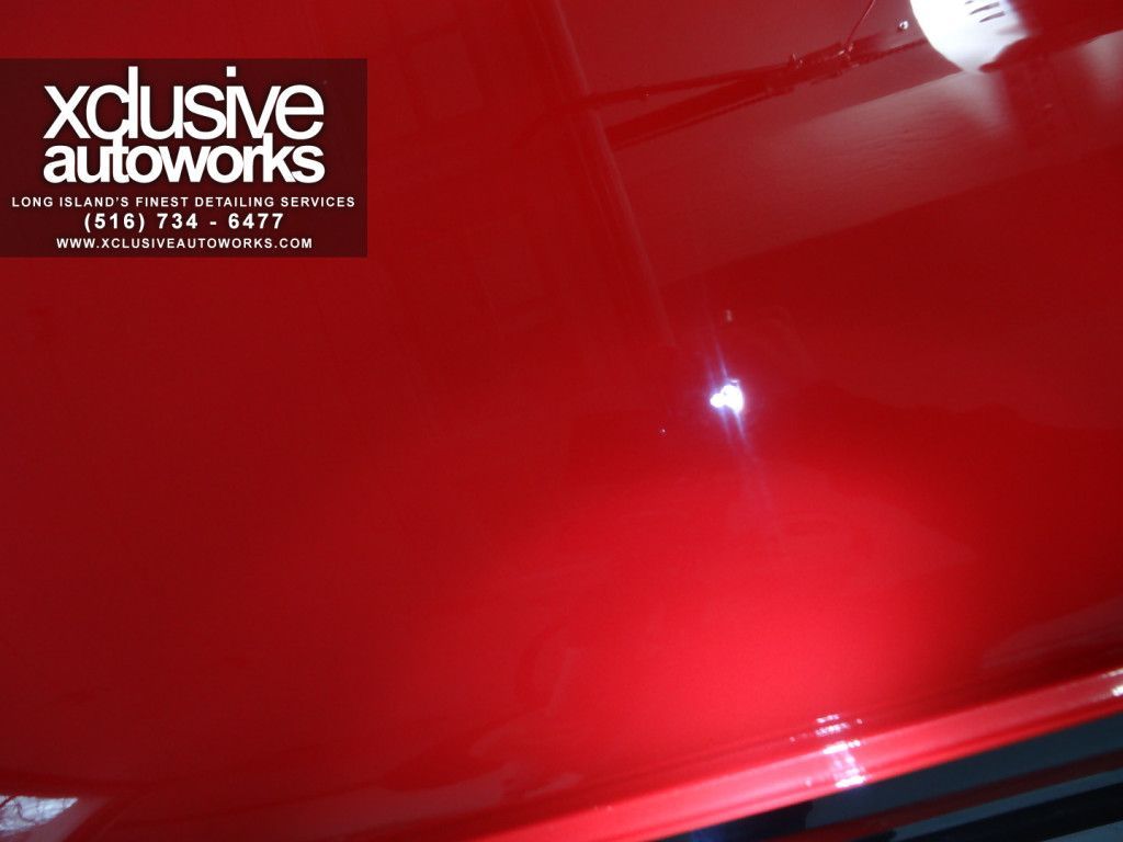 A red car with a xclusive autoworks logo on it