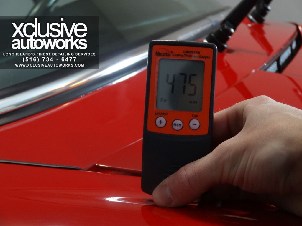 A person is measuring the thickness of a red car