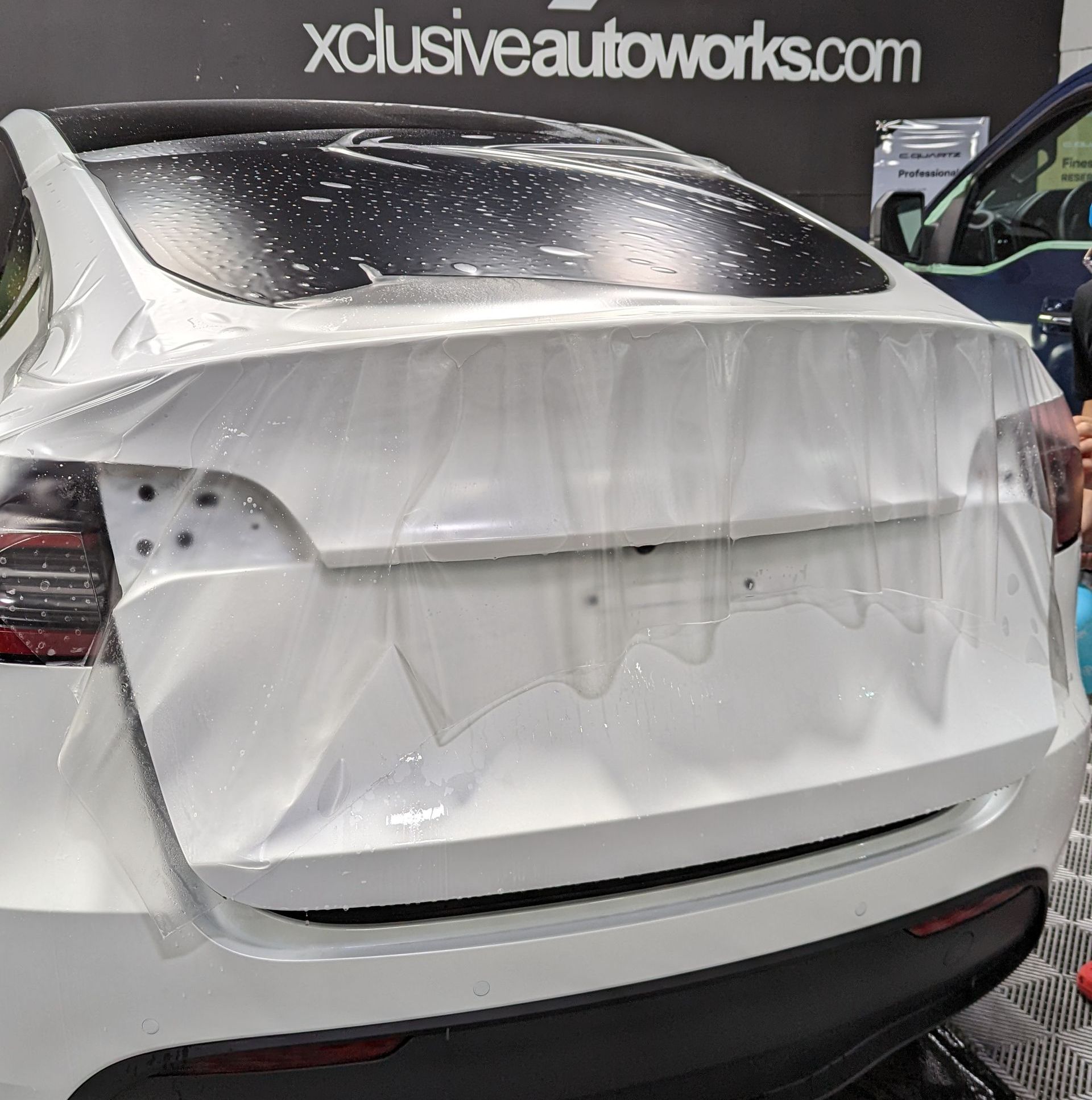 A white tesla model x is wrapped in plastic