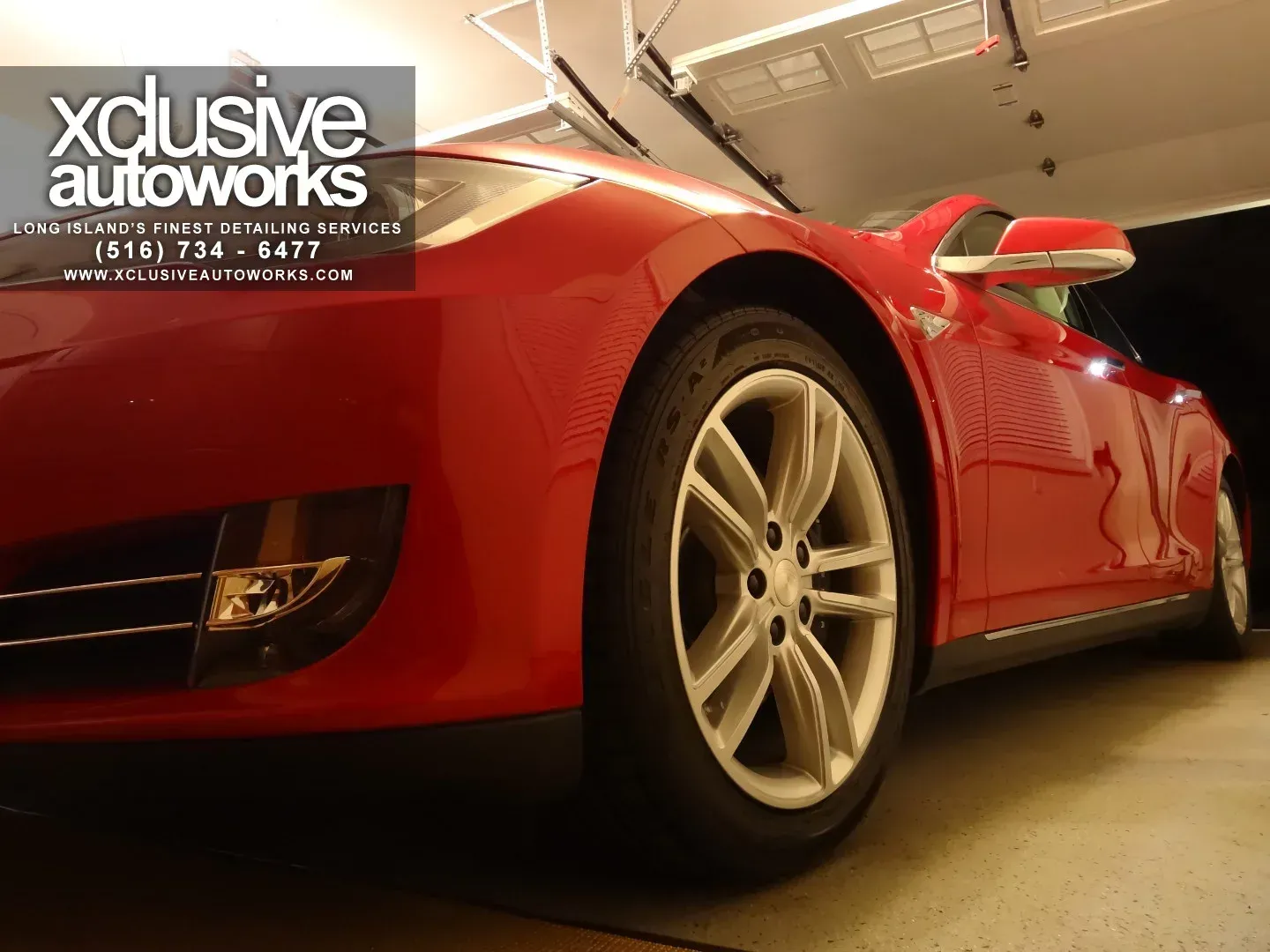 A red car is parked in a garage by xclusive autoworks