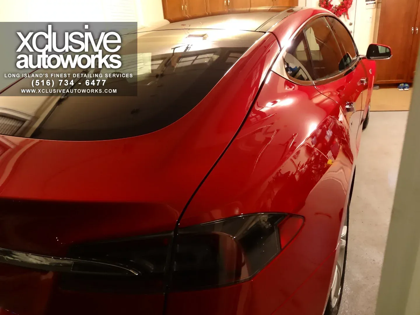 A red car is parked in a garage by xclusive autoworks