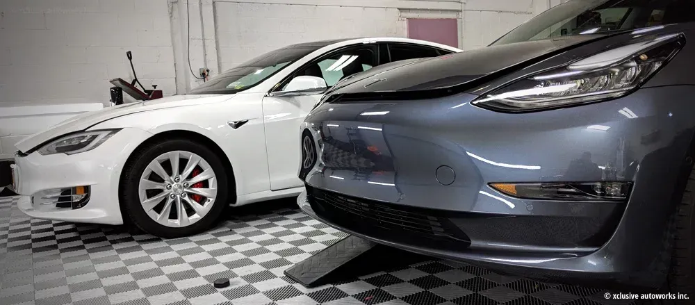 Two tesla cars are parked next to each other in a garage.