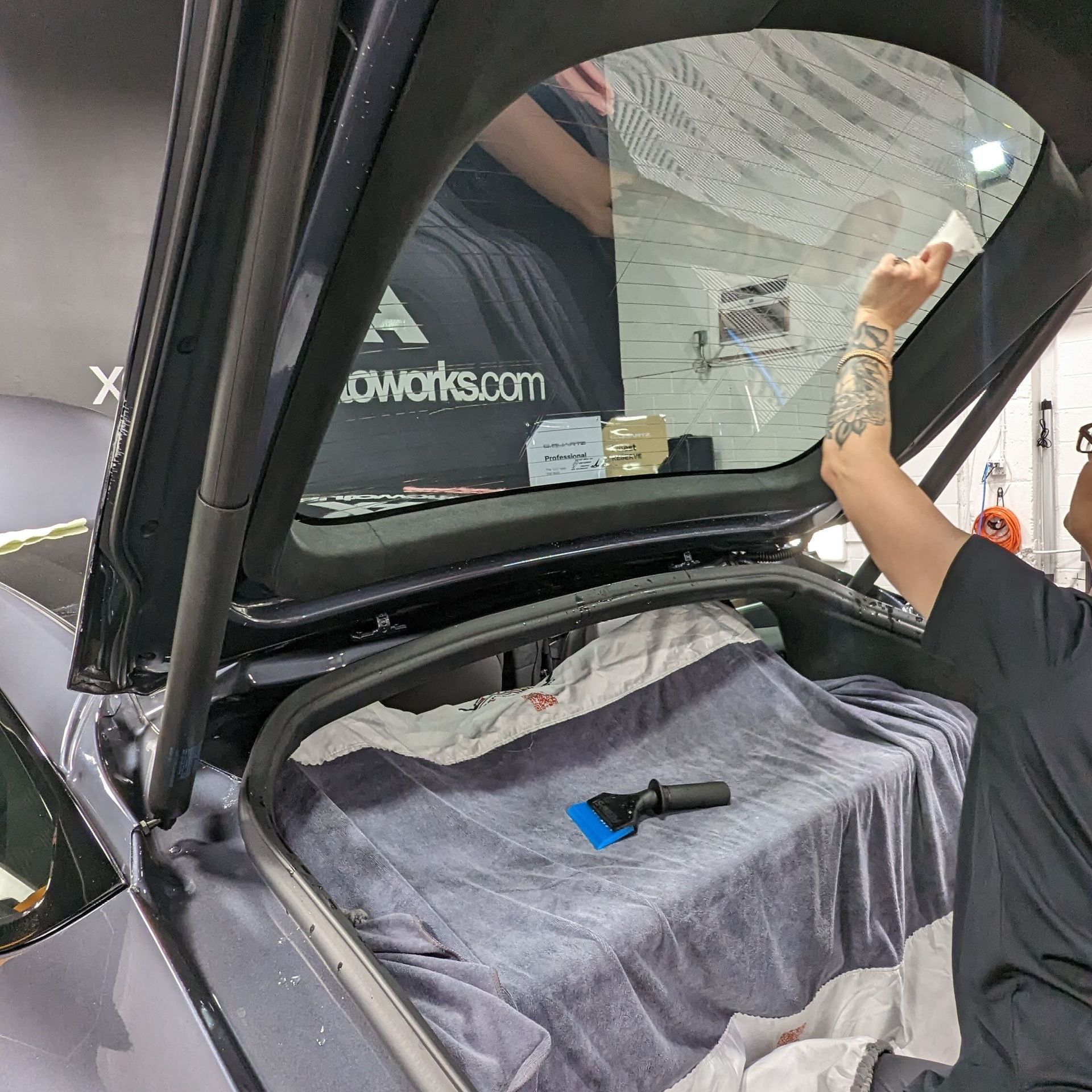 A man is working on the back window of a car