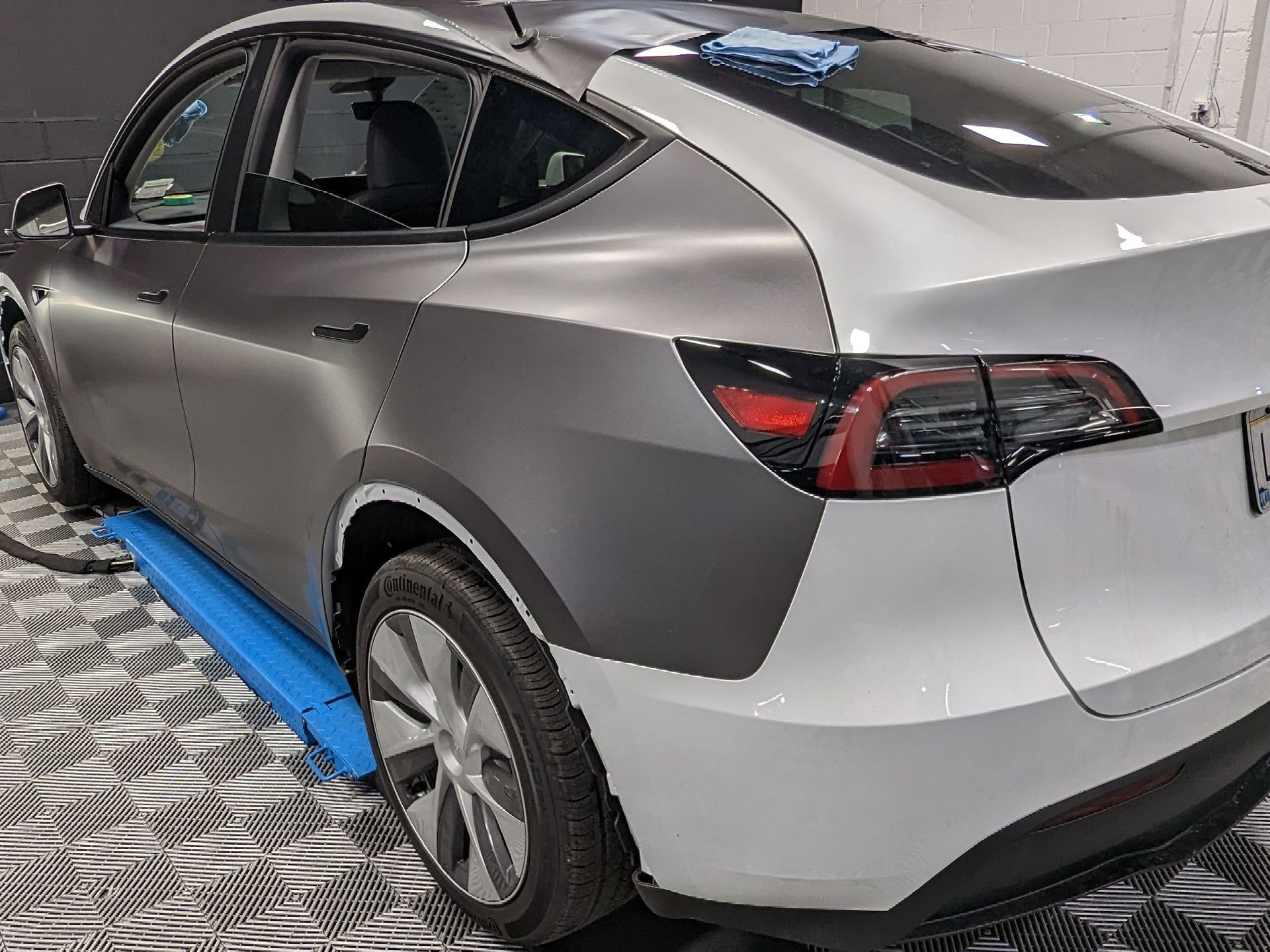 A tesla model y is sitting on a lift in a garage.