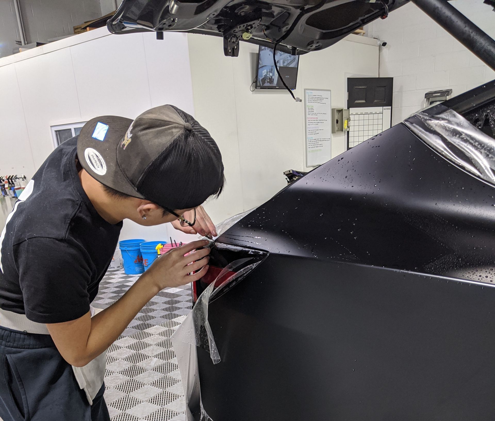 A man is working on a black car in a garage.