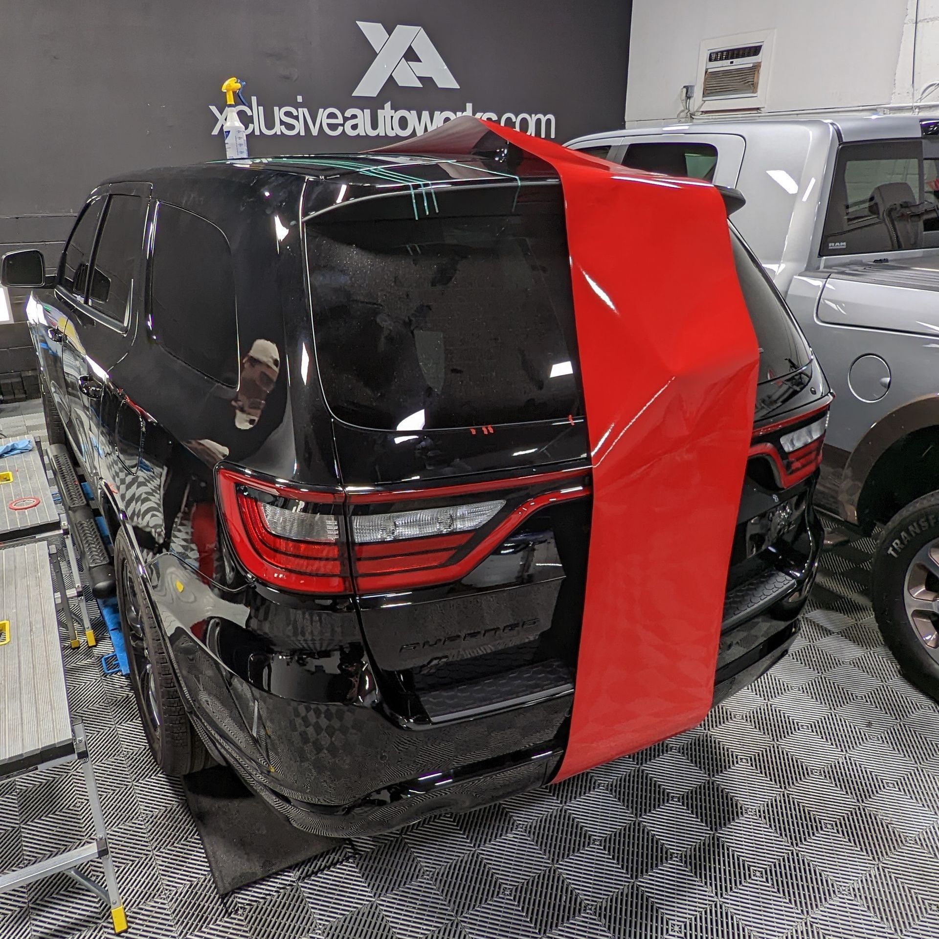 A black car with a red stripe on the back is parked in a garage.