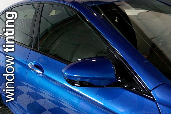 A blue car with the words window tinting on it