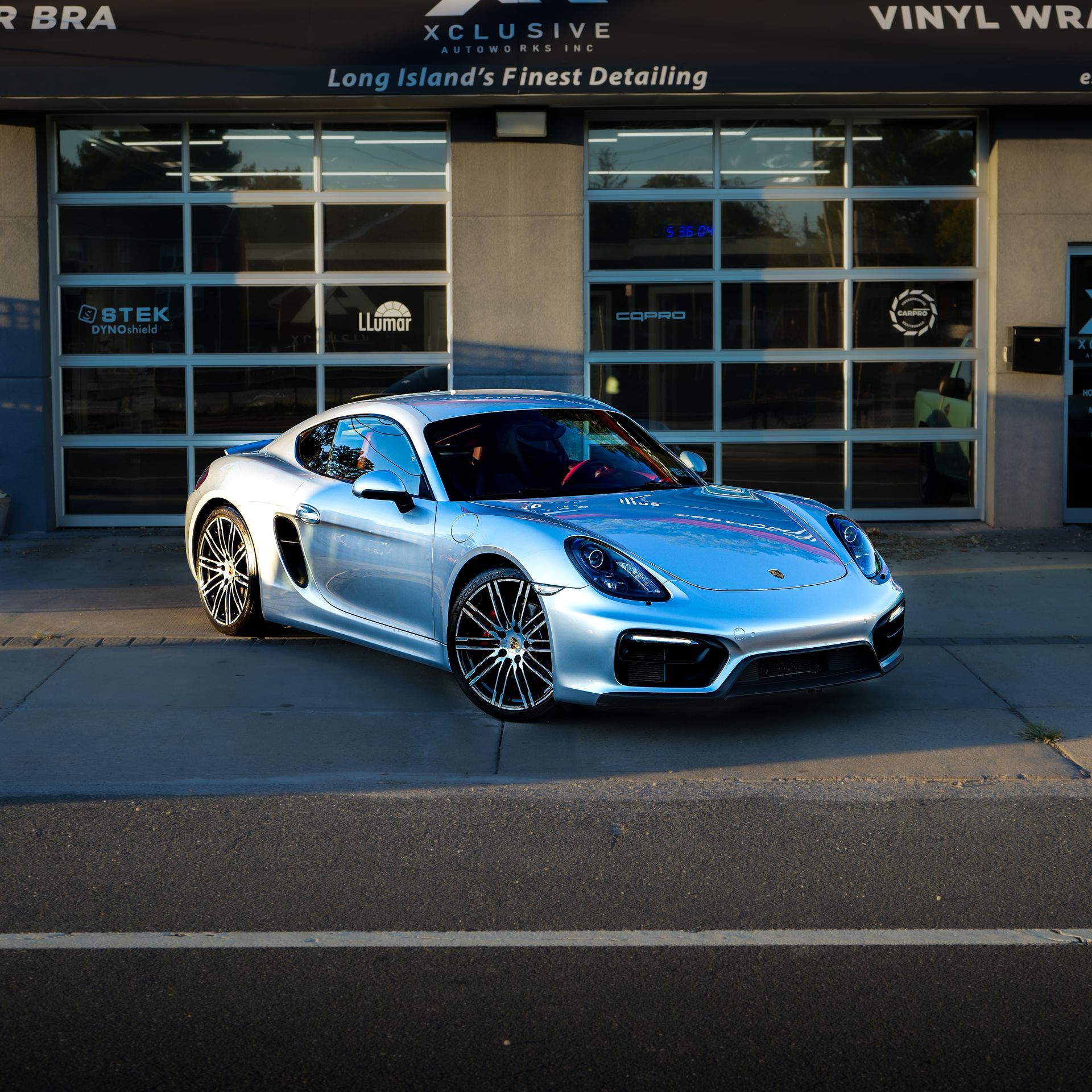 A tesla model 3 is painted in a rainbow of colors and has a red brake caliper.