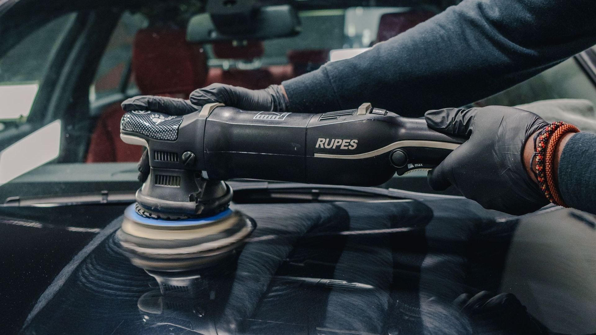 A person is polishing a car with a machine.