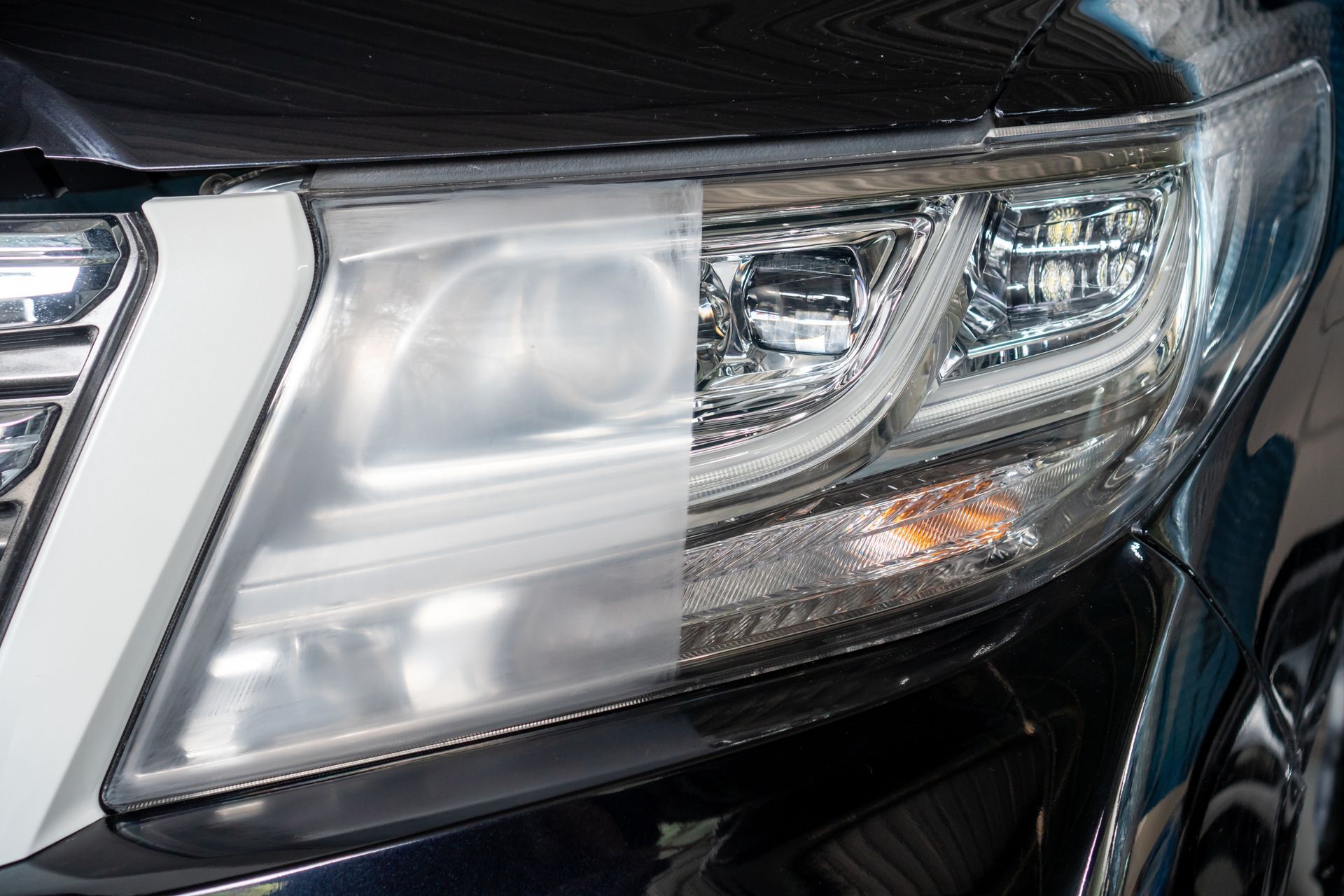 A car headlight split into two sides: one side is dull and cloudy, while the other is restored to clear, polished plastic.