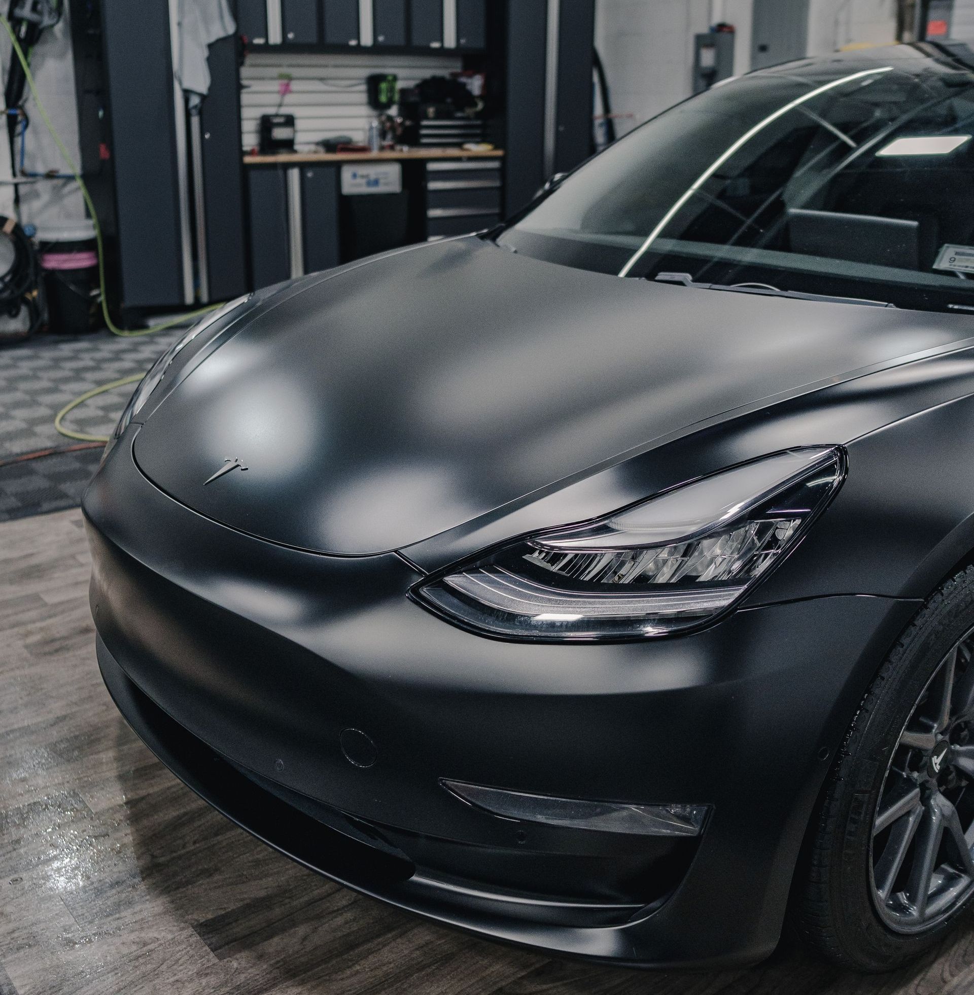 A black tesla model 3 is parked in a garage