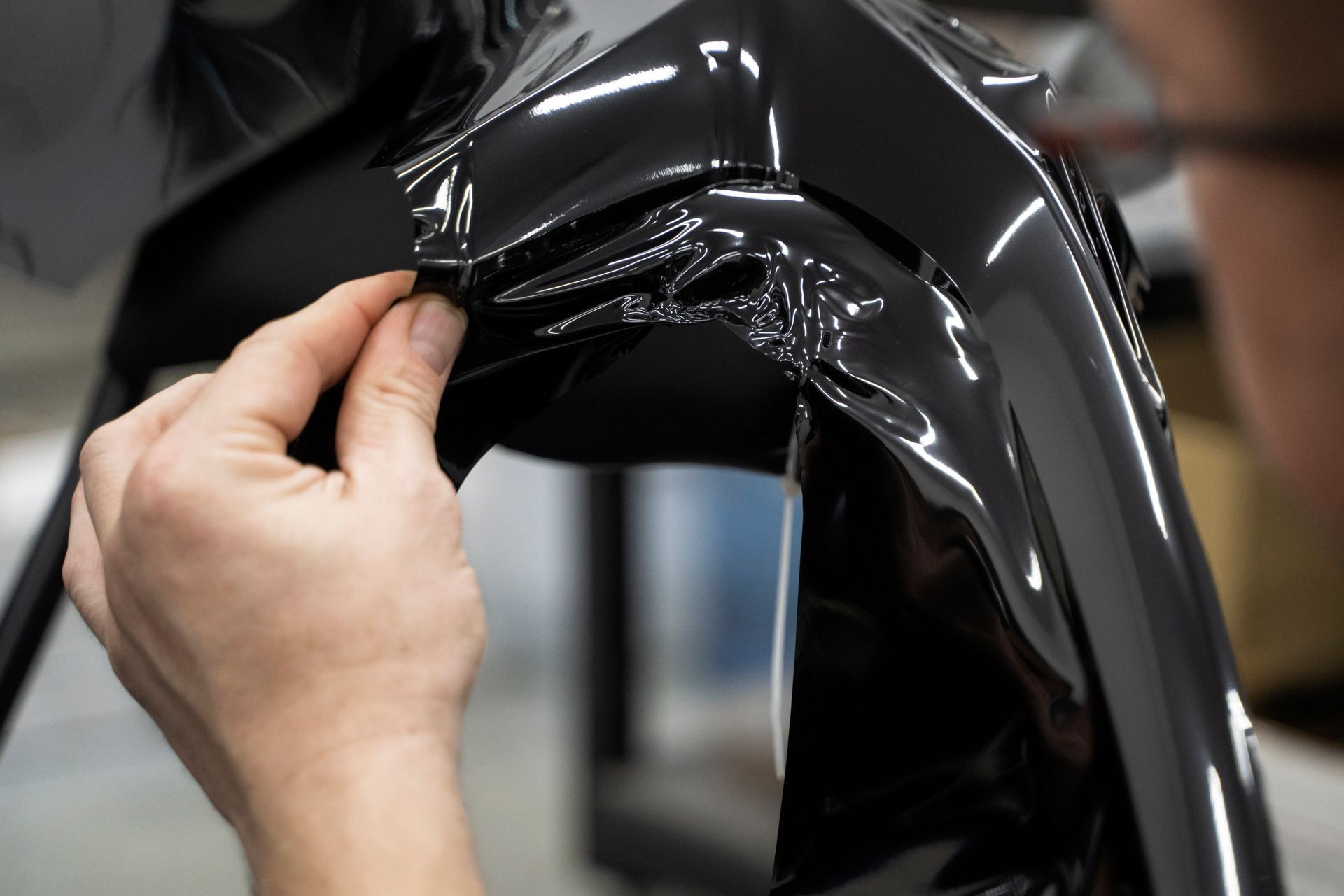 A person is wrapping a piece of plastic on a chair.