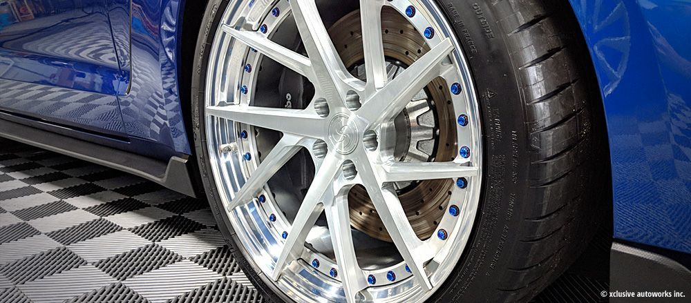 A close up of a car wheel on a checkered floor.