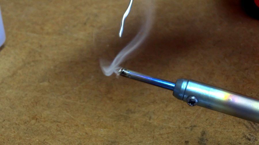 A close up of a soldering iron with smoke coming out of it.