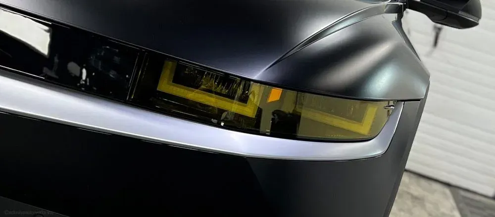 A close up of a black car with a yellow headlight.