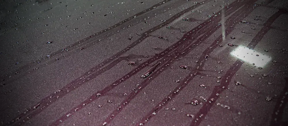 A man is cleaning the hood of a black car with a cloth.