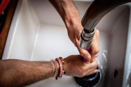 A man is using a plunger to unblock a sink drain.
