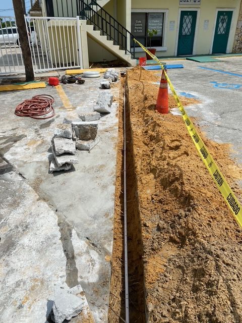 A large hole in the ground is being dug in front of a building.