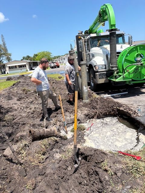 Two men are standing in the dirt next to a green truck.