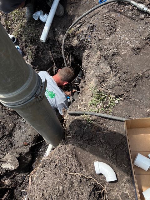 A man is working on a pipe in the dirt.