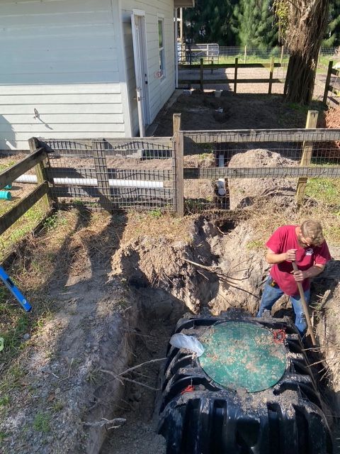 A man is digging a hole in the dirt in front of a house.