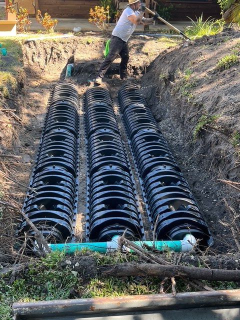 A man is working on a septic system in a yard.