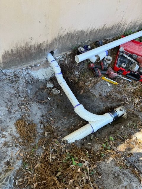 A bunch of pipes are laying on the ground next to a generator.