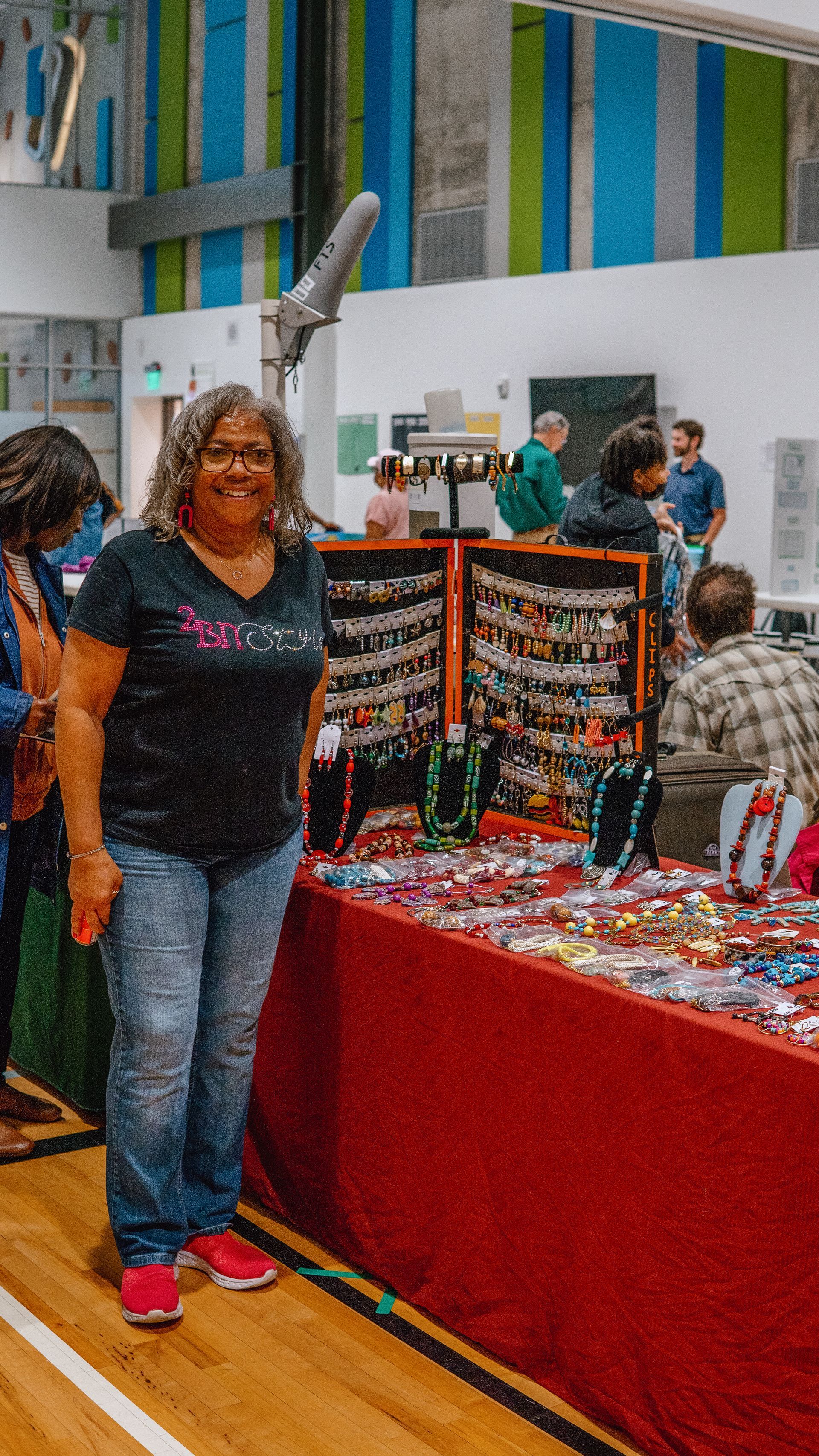A woman is standing in front of a table at a craft fair.