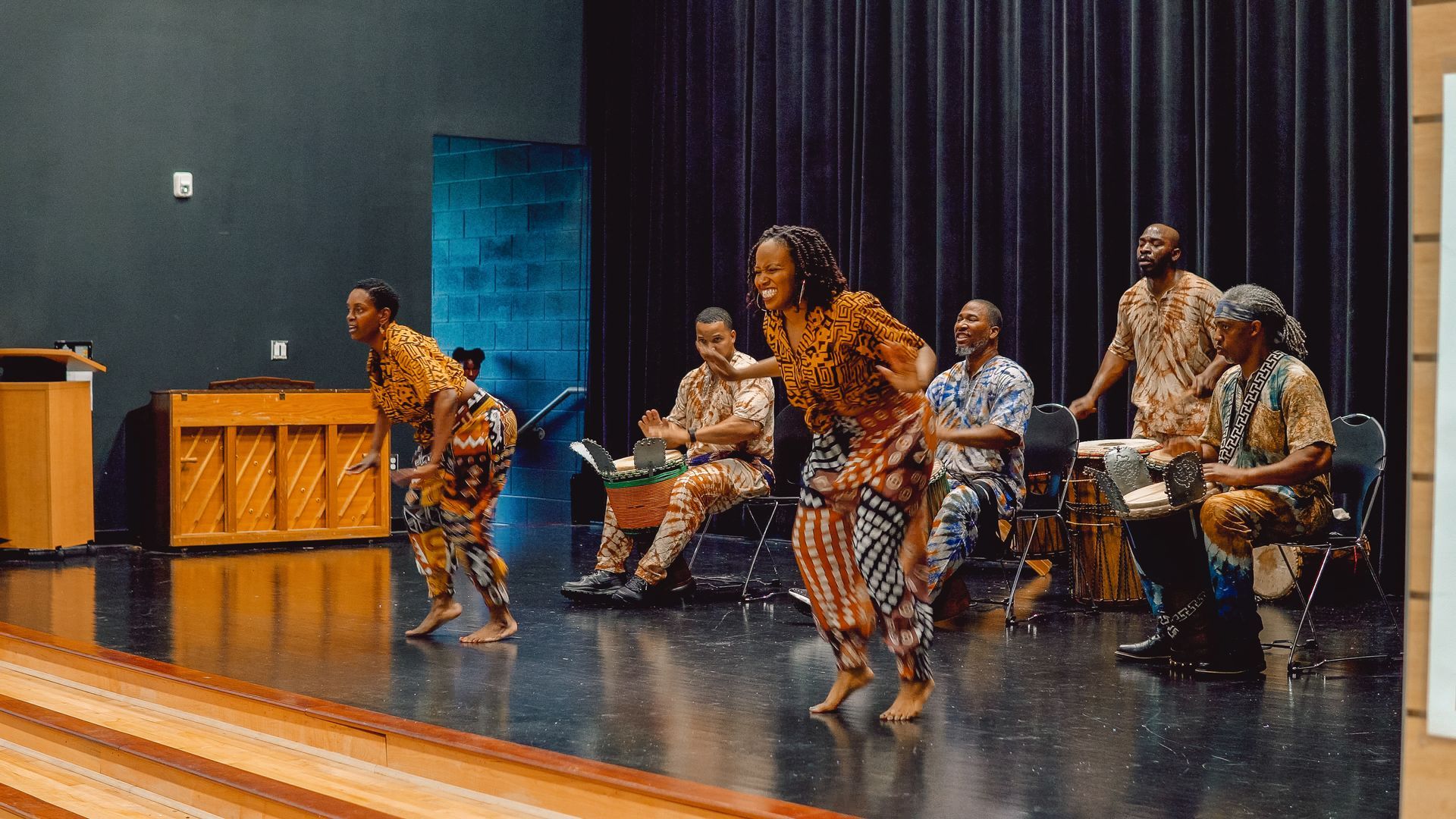 A group of people are dancing on a stage in a room.