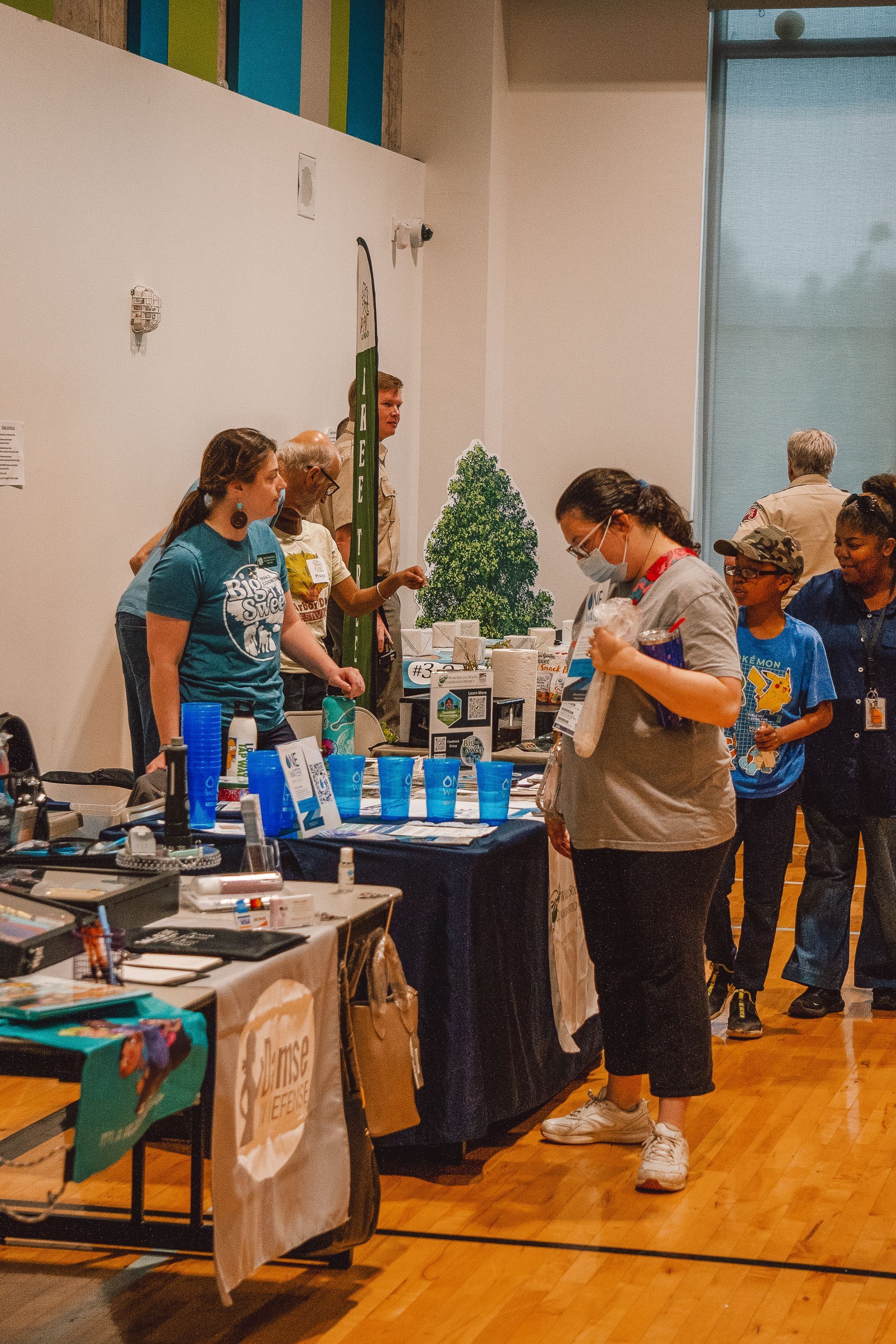 A group of people are standing around a table at a convention.