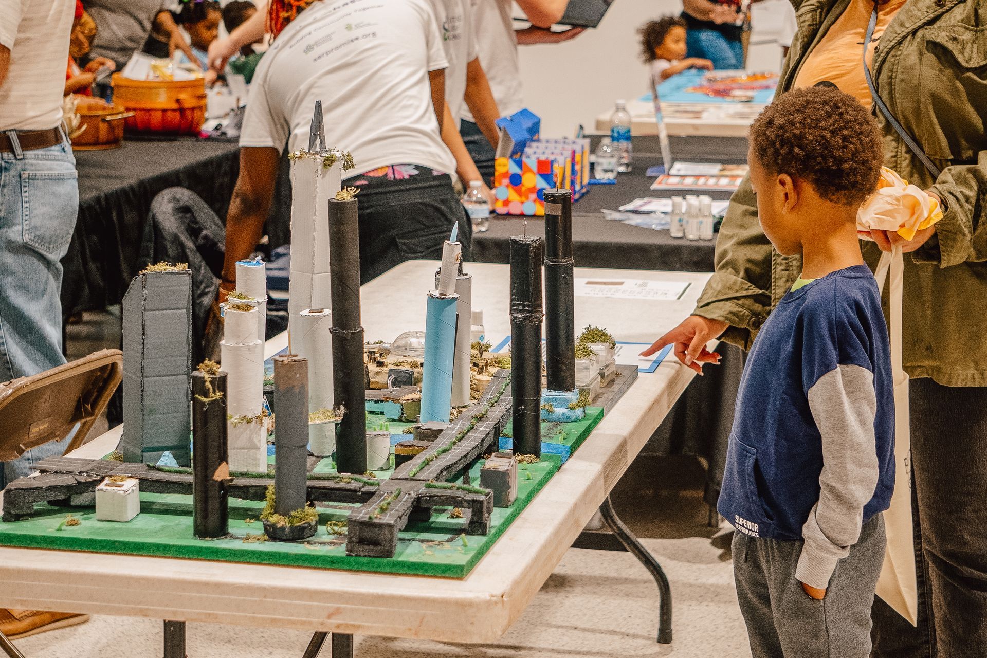 A boy is standing in front of a table with a model of a city on it.