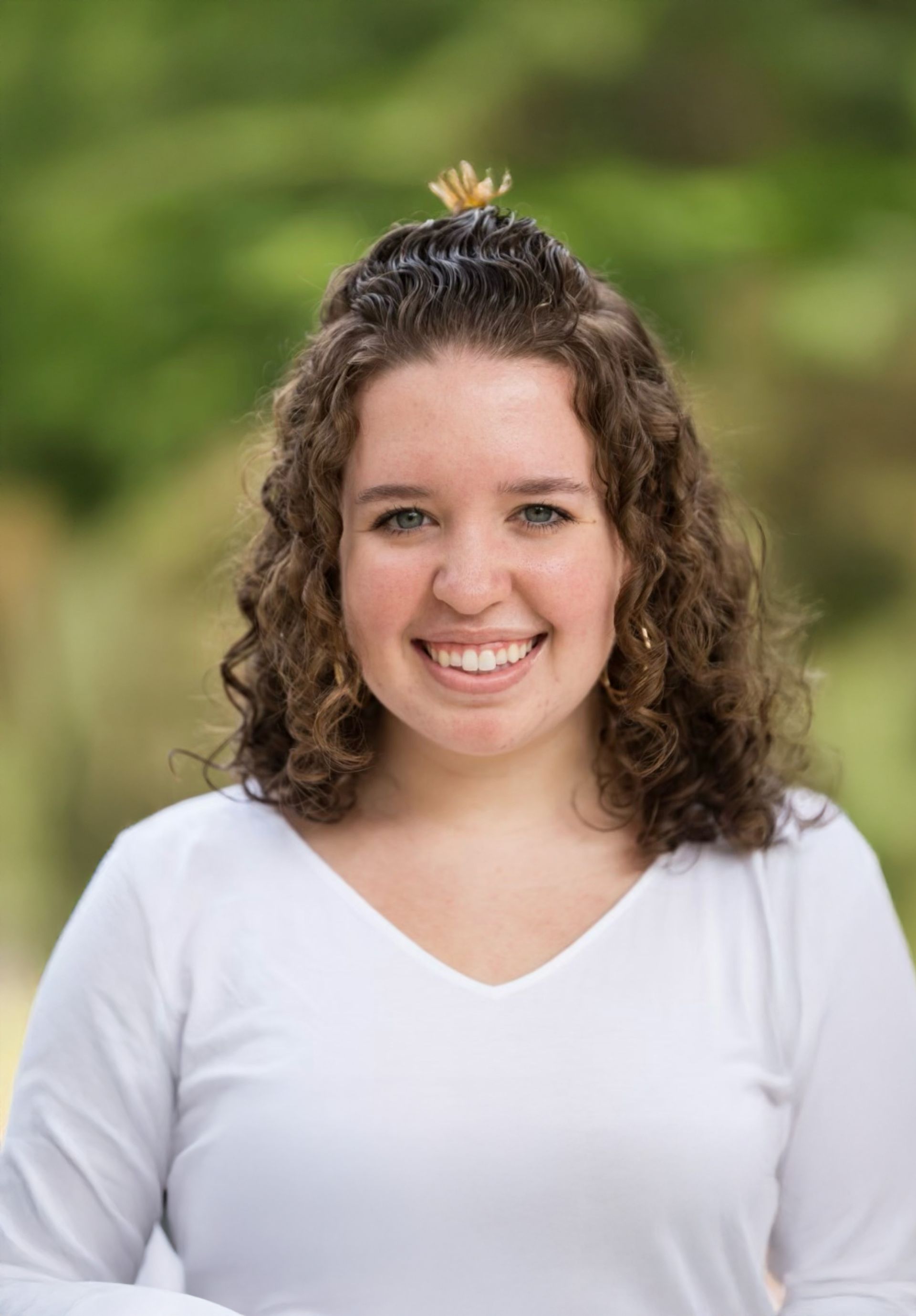A woman with curly hair is wearing a black shirt and smiling.
