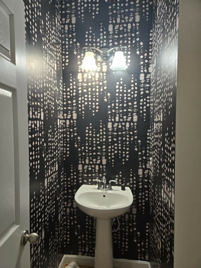A bathroom with a sink and a black and white wallpaper