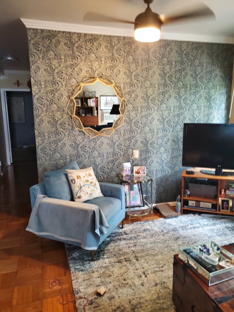 A living room with a couch , chair , television and ceiling fan.
