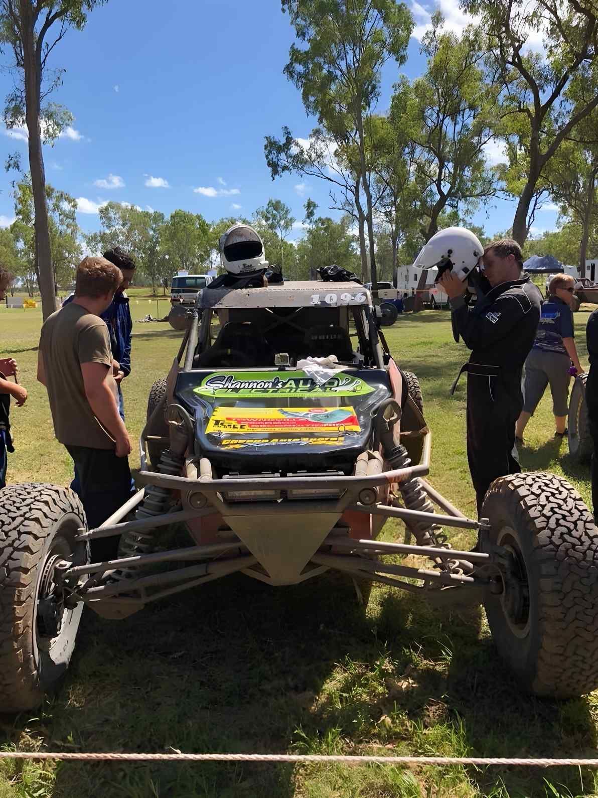 A Customized Off-road Racing Buggy With Its Hood Open, Surrounded by People in a Grassy Field Under a Sunny Sky — Shannon's Auto Electrical in Garbutt, QLD