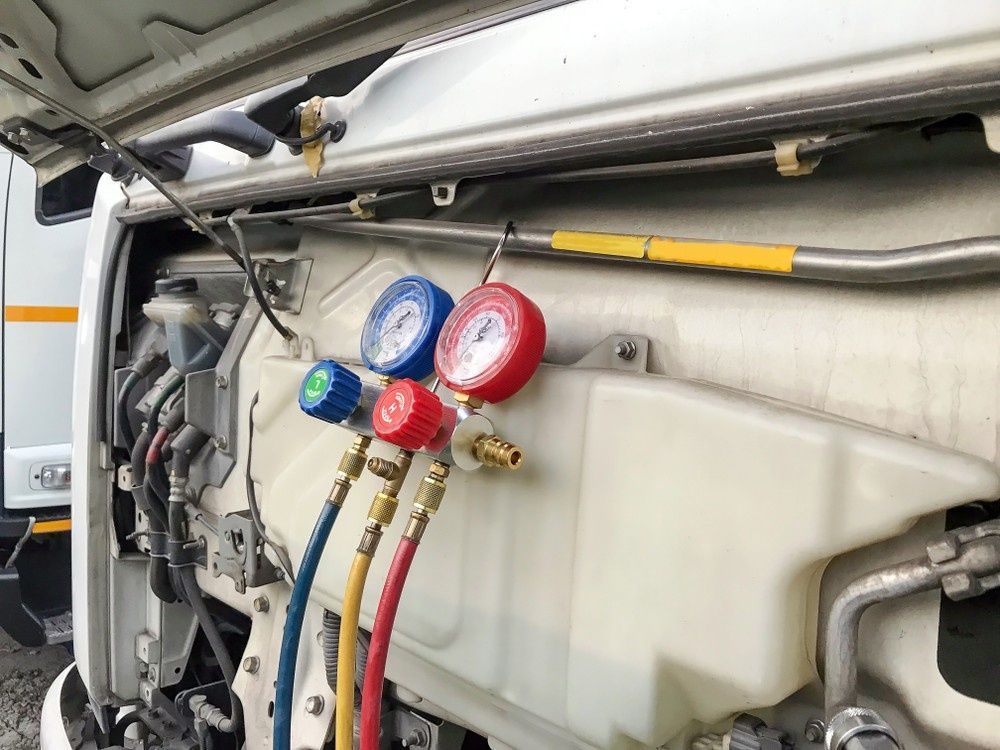 A White Vehicle's Engine Bay With Gauges Connected to an Air Conditioning System; Gauges Are Blue, Red, and Green — Shannon's Auto Electrical in Garbutt, QLD