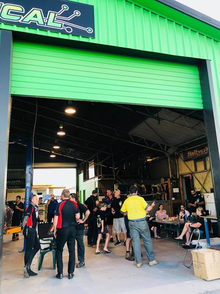 People Gather Inside and Outside a Green Workshop With 