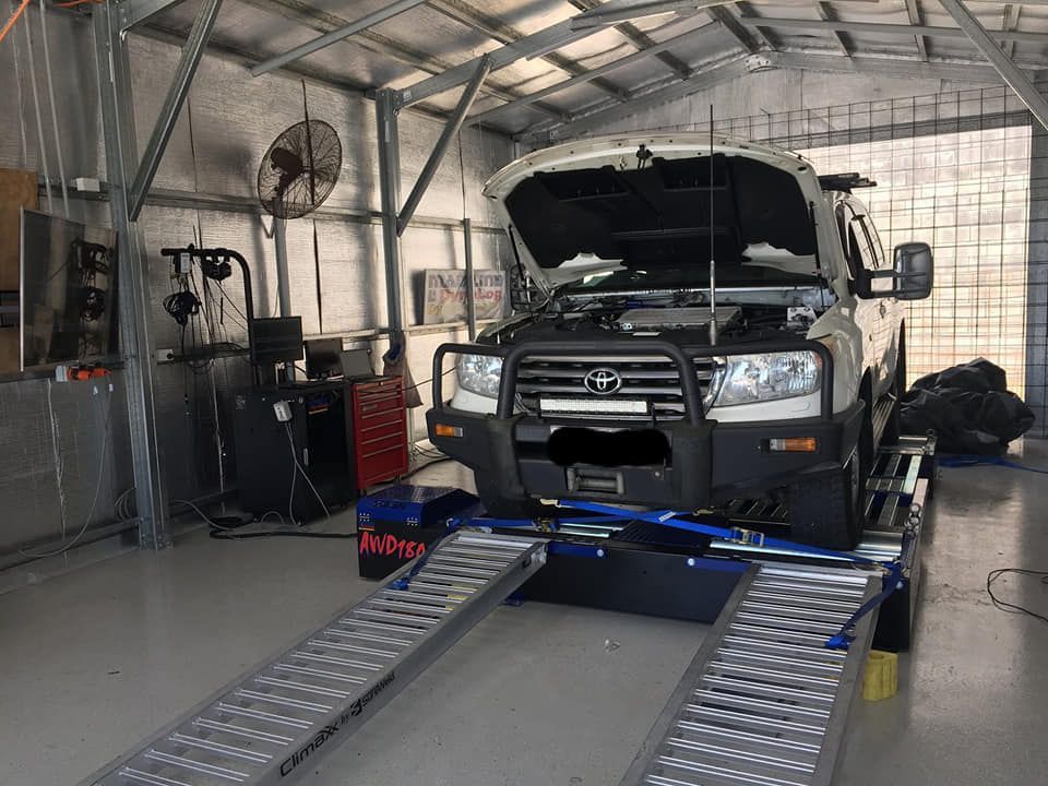 A White Toyota Land Cruiser on a Dynamometer Inside a Workshop With Its Hood Open — Shannon's Auto Electrical in Garbutt, QLD