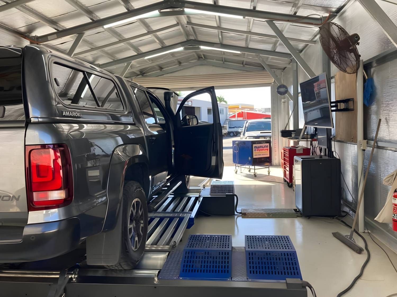 Dark Gray Pickup Truck on a Dynamometer Inside a Workshop. the Driver's Side Door is Open — Shannon's Auto Electrical in Garbutt, QLD