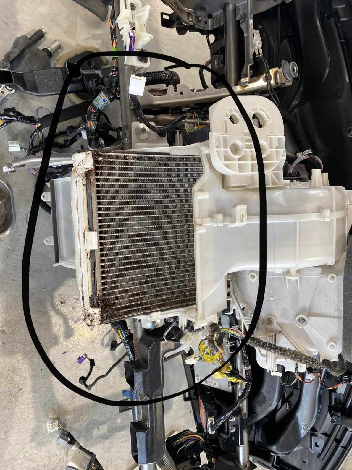 A Disassembled Car Air Conditioning System, With the Evaporator Core Circled in Black. Wires and Other Components Are Scattered Around It — Shannon's Auto Electrical in Garbutt, QLD