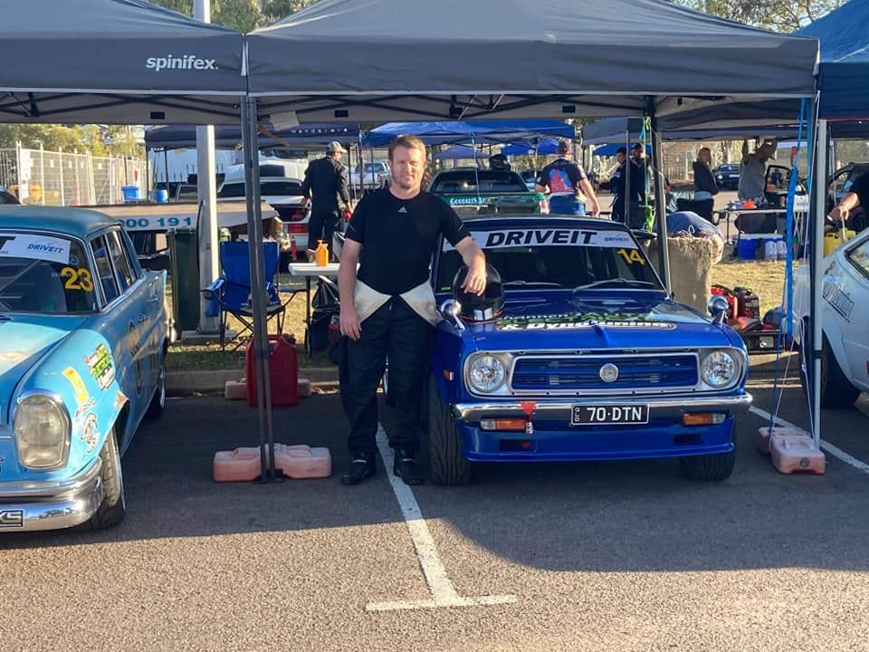 Man Stands Next to a Blue Race Car With 