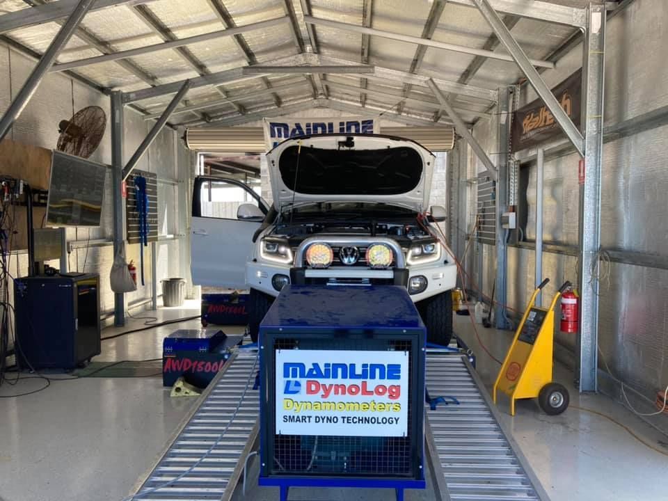 A White Truck on a Dyno in a Shop, Hood Open for Testing. 