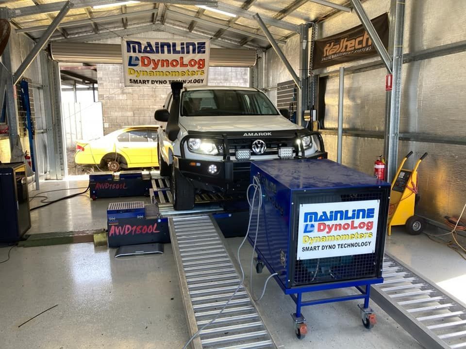 A White Pickup Truck on a Dynamometer Inside a Garage. the Dyno Displays 