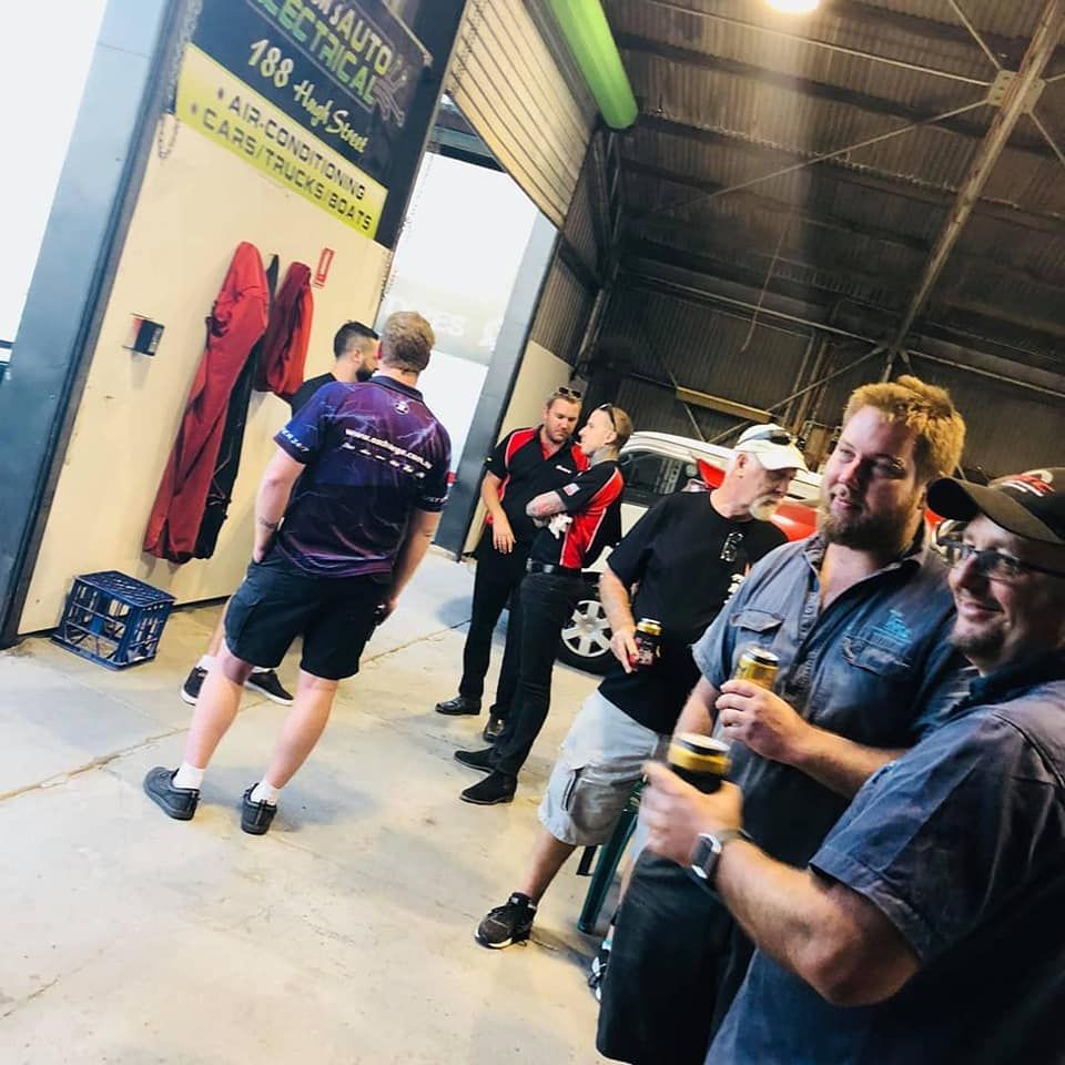 A Group of Mechanics at a Shop Socializing. Men Are Standing Around, Holding Drinks, With Some Wearing Work Attire — Shannon's Auto Electrical in Garbutt, QLD