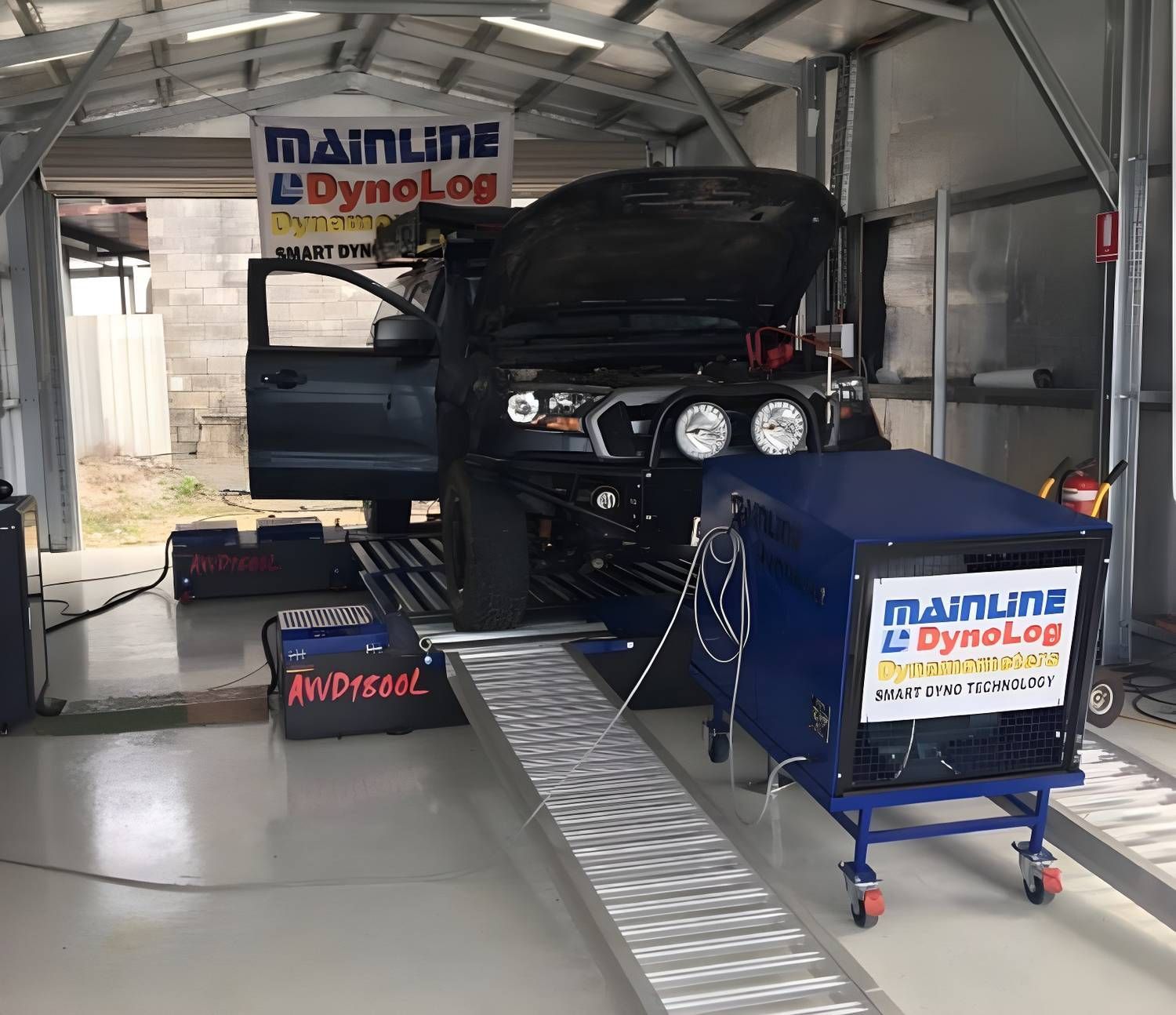 A Dark-colored Truck on a Dynamometer in a Garage, Hood Open. a Person is Likely Doing a Performance Test — Shannon's Auto Electrical in Garbutt, QLD