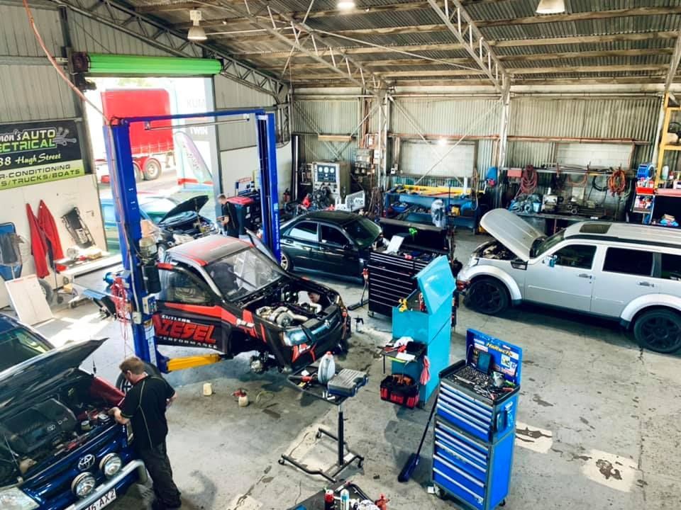 Interior View of a Busy Auto Repair Shop. Multiple Cars Are in Various Stages of Repair, With Mechanics Working on Them — Shannon's Auto Electrical in Garbutt, QLD