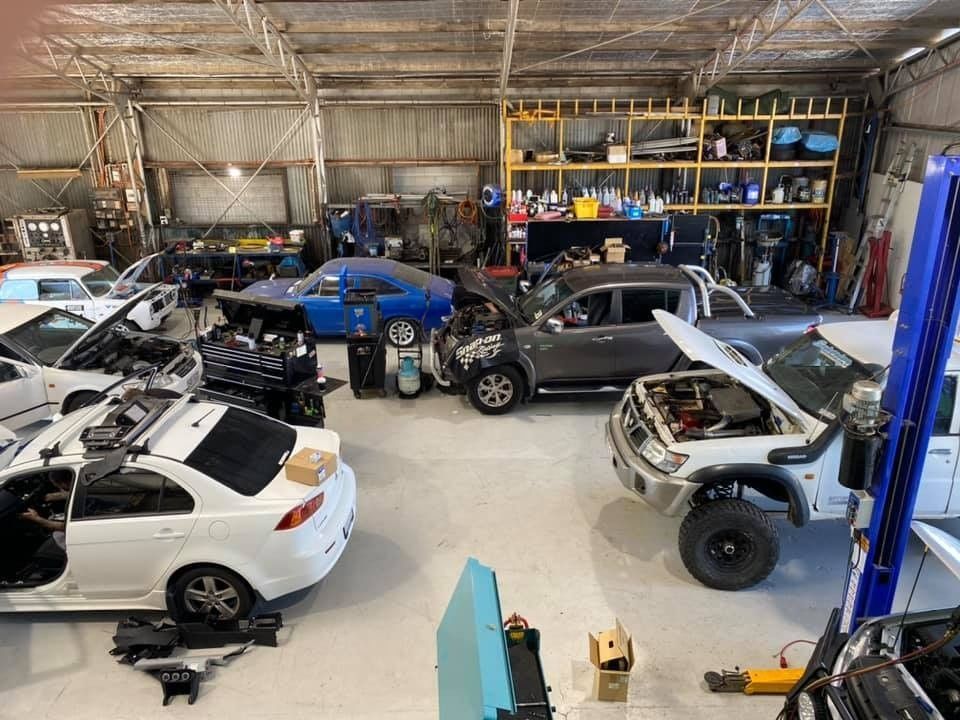 Inside a Busy Auto Repair Shop: Multiple Vehicles With Open Hoods and Car Parts Scattered — Shannon's Auto Electrical in Garbutt, QLD