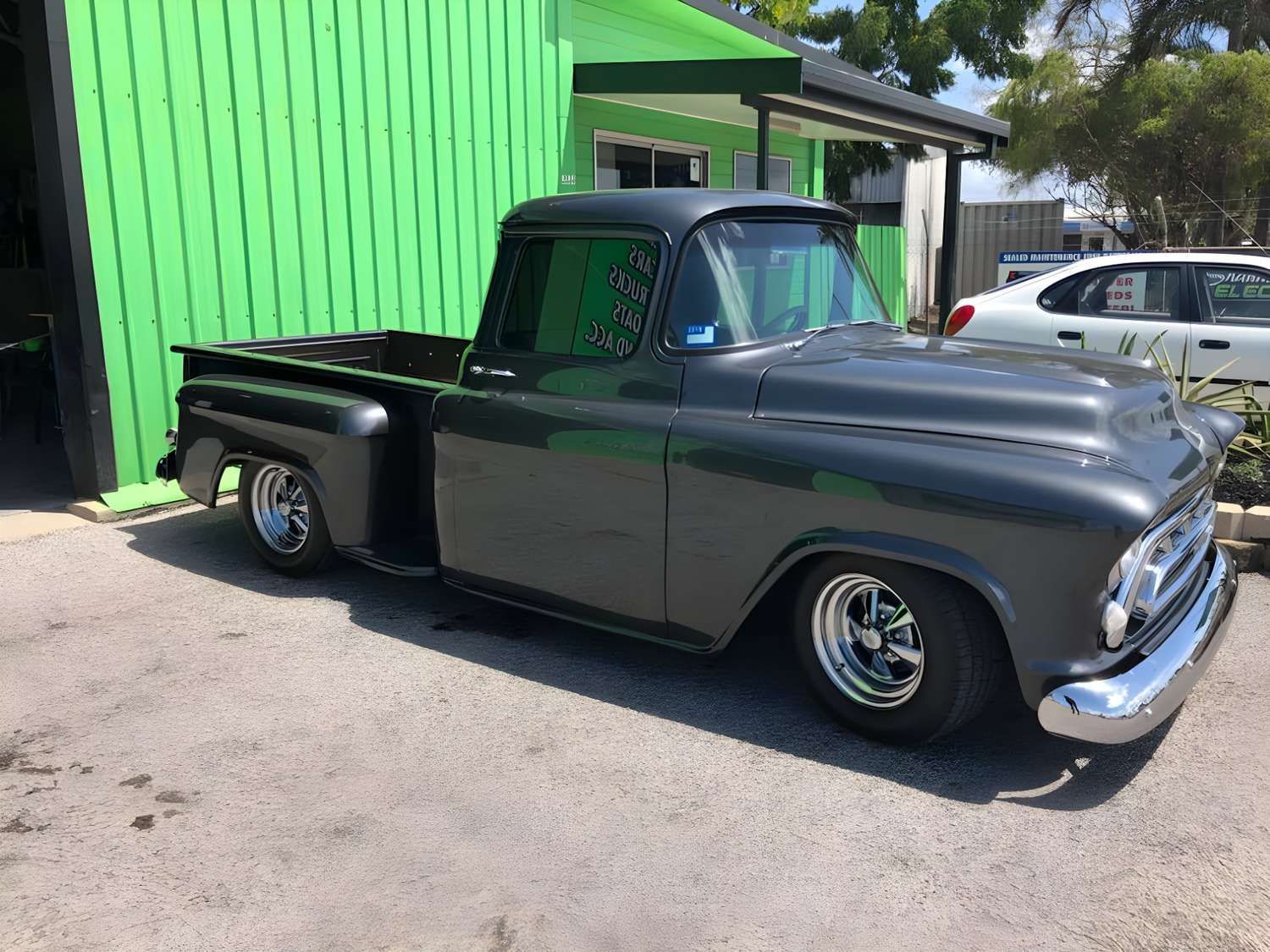 Dark Gray Classic Pickup Truck Parked in Front of a Green Building. It Has Chrome Bumpers and Custom Wheels — Shannon's Auto Electrical in Garbutt, QLD