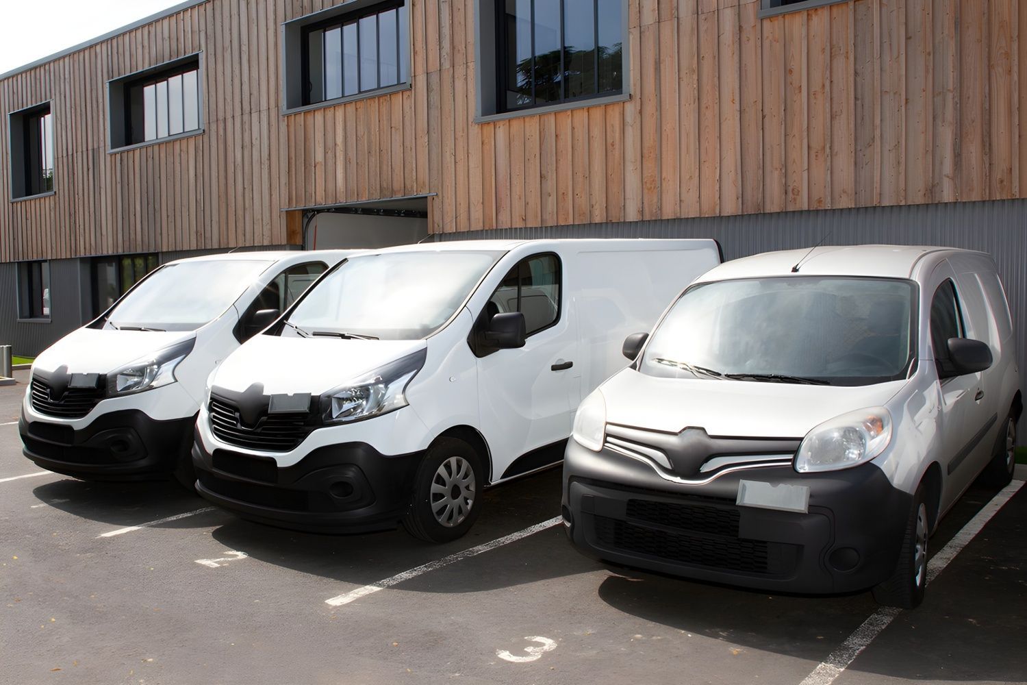 Three White Delivery Vans Parked in a Lot in Front of a Wooden Building — Shannon's Auto Electrical in Garbutt, QLD