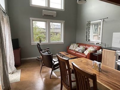 Bright living room with wood table, leather sofa, chairs, and large windows with gray walls